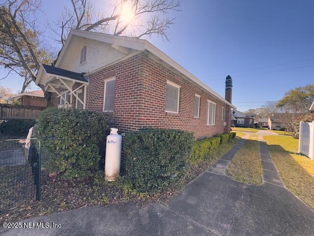 view of side of home with fence and brick siding