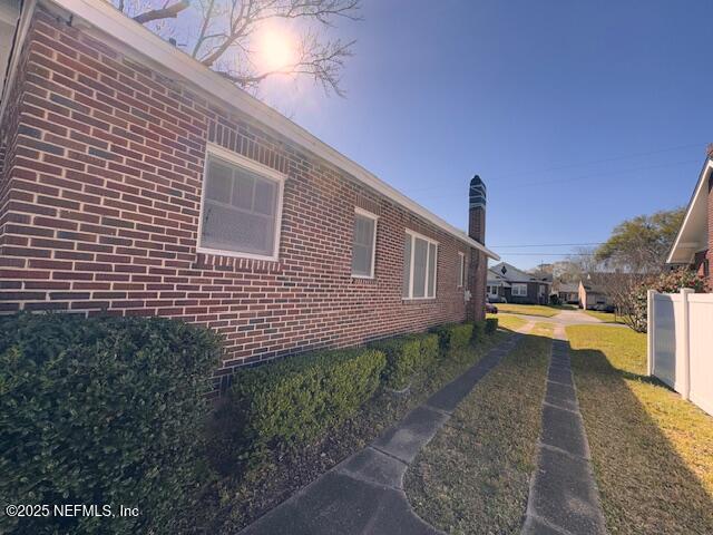 view of property exterior with brick siding and fence