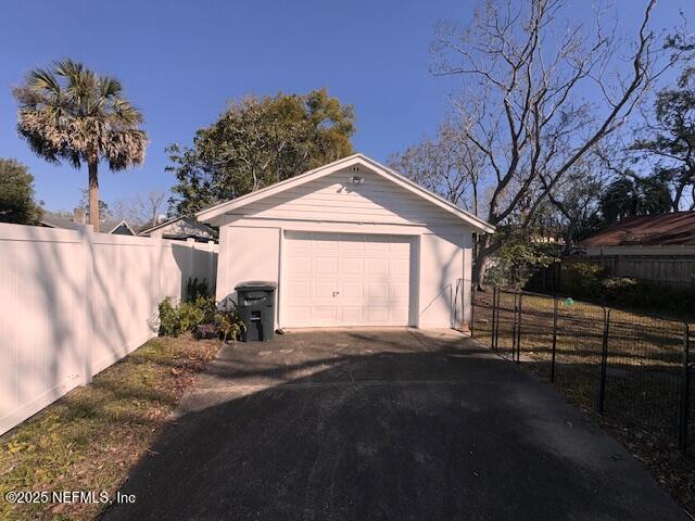 detached garage featuring driveway and fence