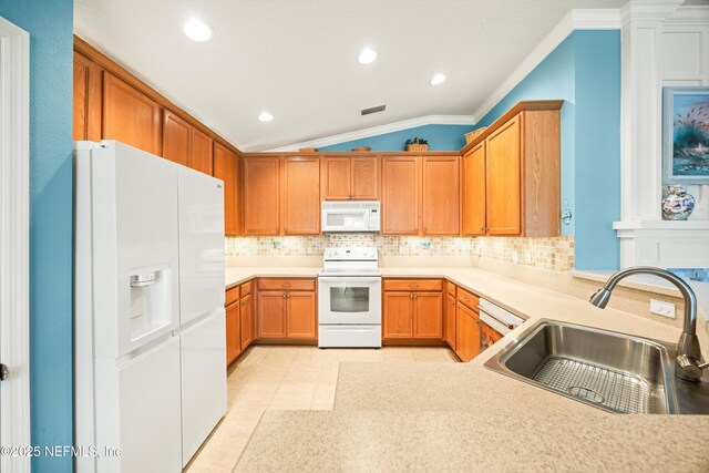 kitchen with lofted ceiling, white appliances, backsplash, and a sink