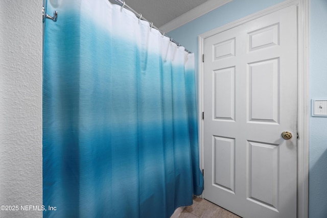 full bathroom featuring a shower with shower curtain, ornamental molding, and tile patterned floors