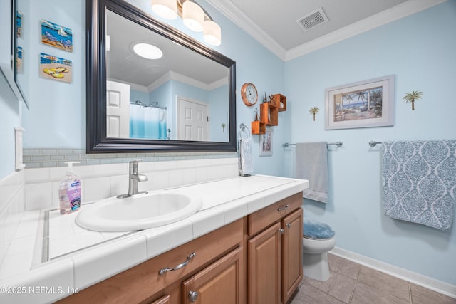 bathroom featuring toilet, vanity, baseboards, visible vents, and crown molding