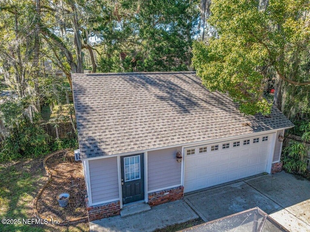 view of front of house featuring a garage, brick siding, concrete driveway, and roof with shingles