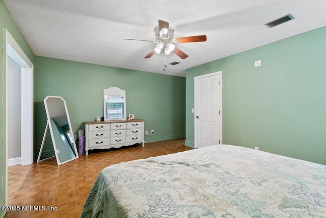 bedroom featuring a textured ceiling, ceiling fan, visible vents, and baseboards