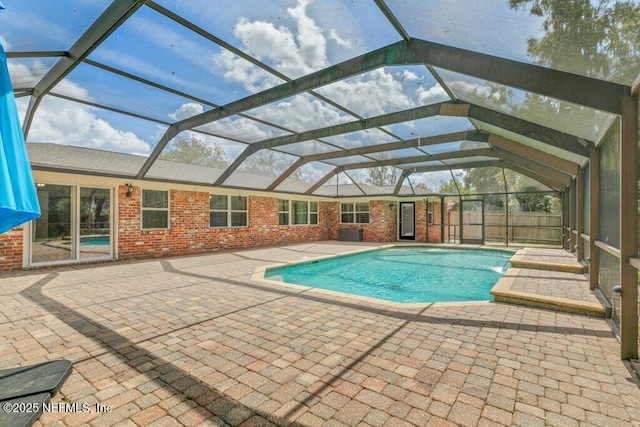 pool with glass enclosure, a patio area, and fence