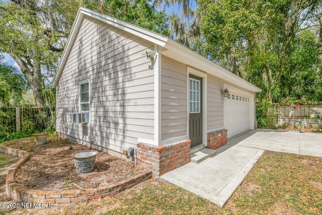 detached garage featuring cooling unit and fence