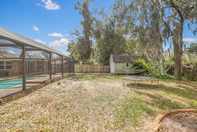 view of yard with a storage shed, a fenced in pool, glass enclosure, a fenced backyard, and an outbuilding