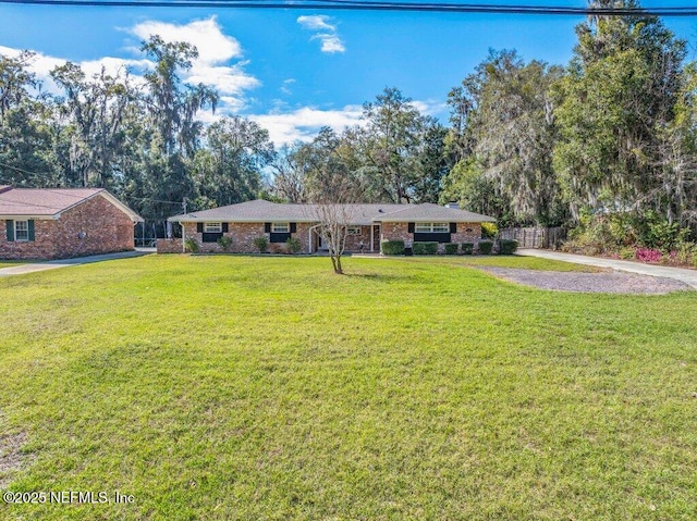 ranch-style house with a front yard, brick siding, and fence