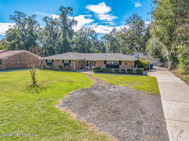 single story home featuring driveway, a front lawn, and brick siding