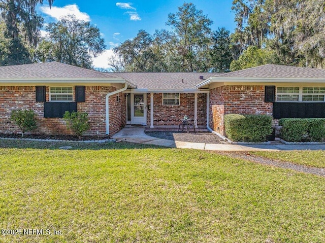 ranch-style house featuring brick siding, a front lawn, and roof with shingles