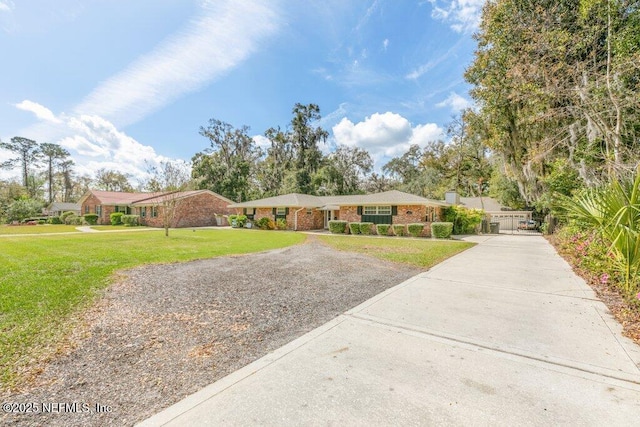 single story home featuring a chimney, a front lawn, concrete driveway, and brick siding