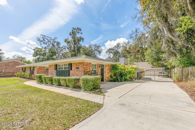 ranch-style home with brick siding, concrete driveway, a gate, a chimney, and a front yard