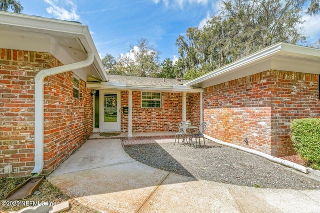 property entrance featuring a patio area and brick siding