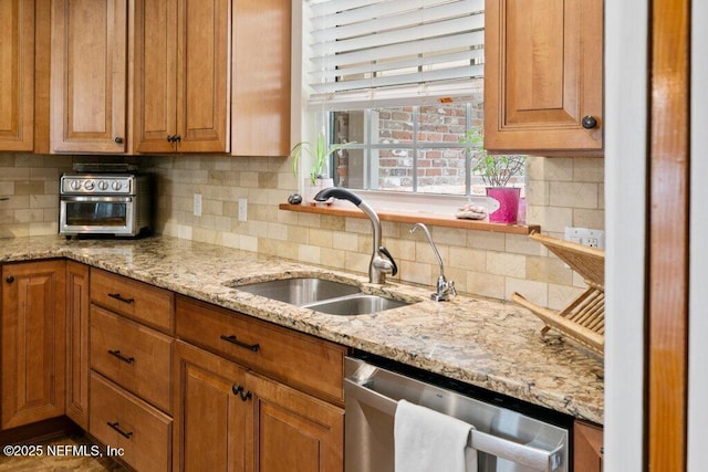 kitchen featuring a sink, light stone countertops, tasteful backsplash, and dishwasher