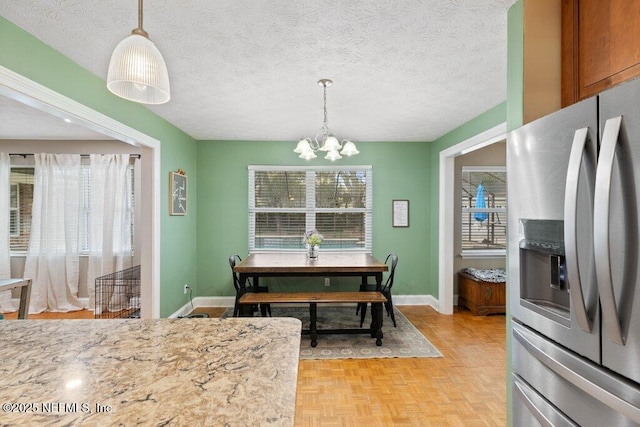 dining room with a textured ceiling, baseboards, and an inviting chandelier