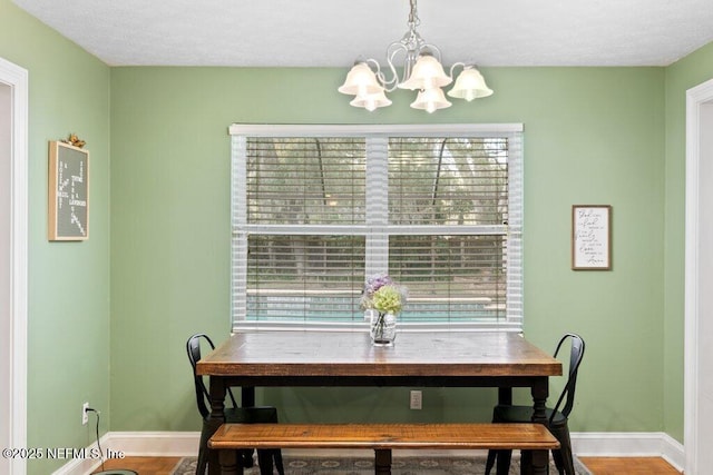 dining space featuring plenty of natural light, baseboards, a chandelier, and wood finished floors