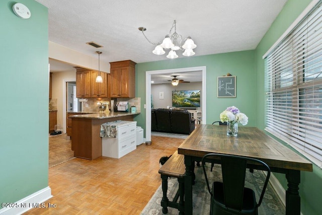 kitchen featuring decorative light fixtures, visible vents, backsplash, brown cabinetry, and a textured ceiling