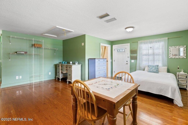 bedroom featuring attic access, a textured ceiling, visible vents, and wood finished floors