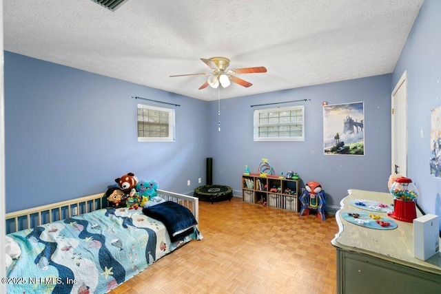 bedroom featuring a textured ceiling, ceiling fan, multiple windows, and visible vents