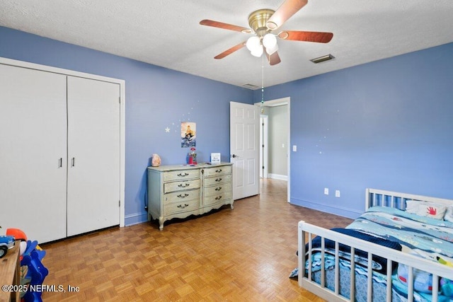 bedroom featuring a ceiling fan, baseboards, visible vents, and a textured ceiling