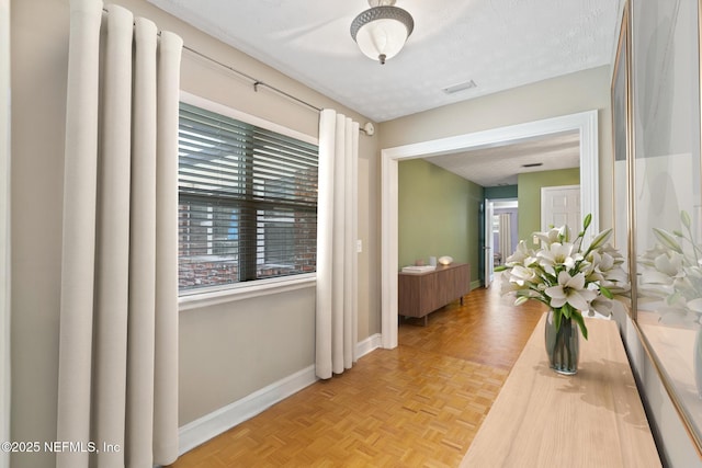 hall featuring a textured ceiling and baseboards