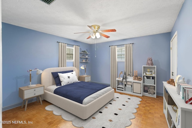 bedroom featuring a textured ceiling, a ceiling fan, visible vents, and baseboards