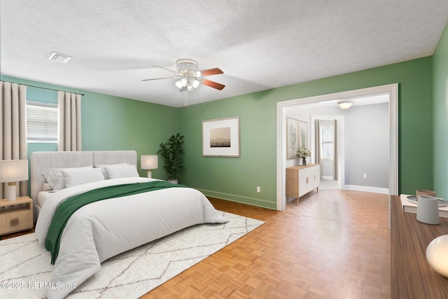 bedroom with visible vents, ceiling fan, a textured ceiling, and baseboards