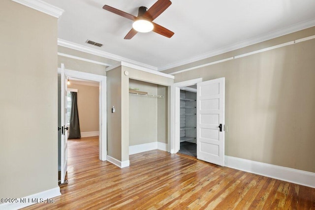 unfurnished bedroom with visible vents, baseboards, light wood-style floors, ornamental molding, and a closet