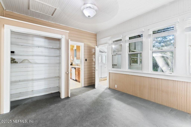 unfurnished bedroom with carpet floors, ensuite bath, and wooden walls