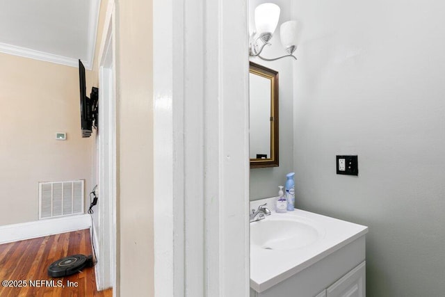 bathroom with visible vents, crown molding, vanity, and wood finished floors