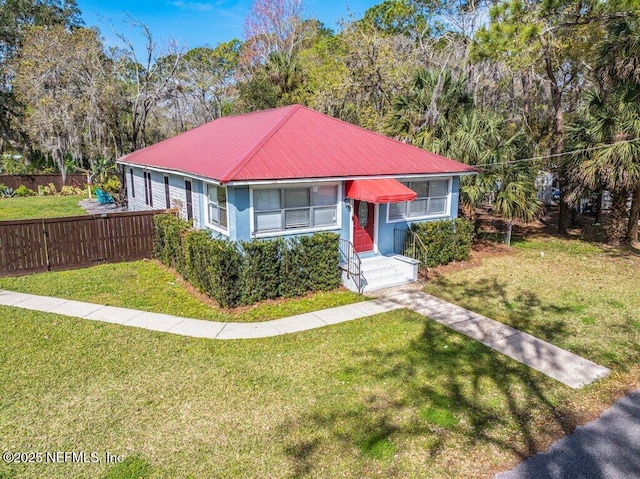 view of front of property with metal roof, a front yard, and fence