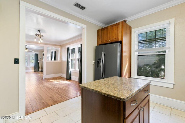 kitchen with visible vents, stainless steel fridge with ice dispenser, a kitchen island, light stone countertops, and crown molding