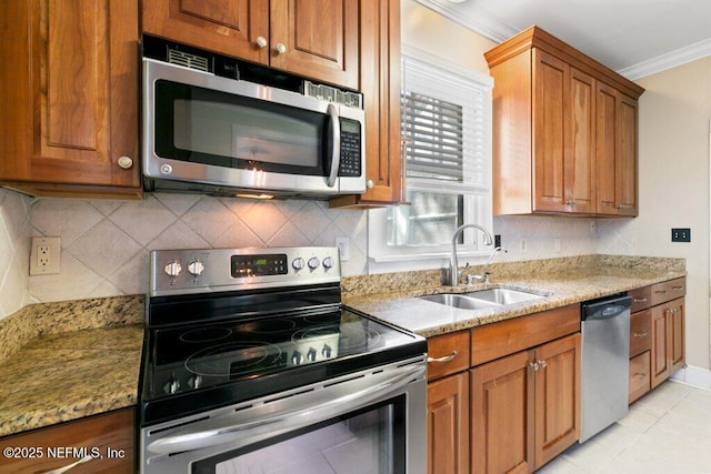 kitchen with crown molding, stainless steel appliances, brown cabinetry, a sink, and light stone countertops