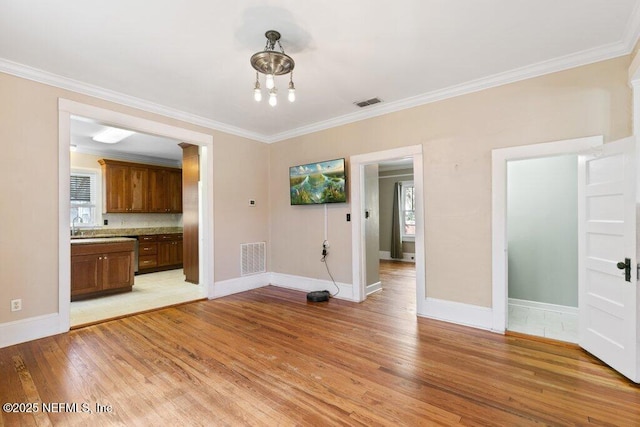 unfurnished dining area featuring light wood finished floors, visible vents, and crown molding