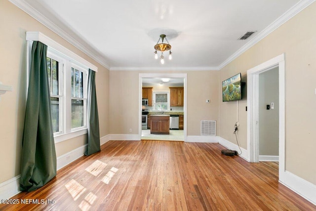 empty room featuring ornamental molding, visible vents, light wood-style flooring, and baseboards