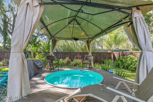 view of pool with a deck, grilling area, and a fenced backyard