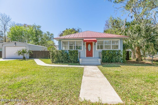 bungalow featuring a garage, metal roof, fence, a front yard, and stucco siding