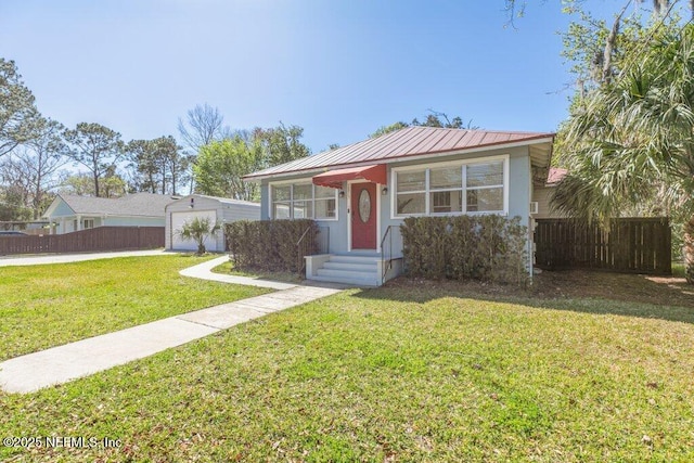 view of front of house with a garage, fence, metal roof, and a front yard