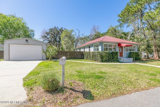 view of front of home featuring a detached garage, metal roof, fence, an outdoor structure, and a front lawn