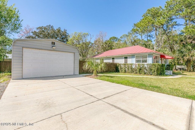 view of front of house featuring a garage, fence, a front lawn, and an outbuilding