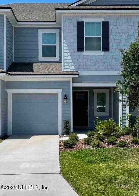 view of front of property featuring an attached garage, roof with shingles, and driveway