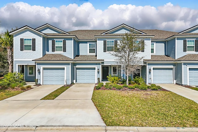 multi unit property featuring concrete driveway, a front lawn, and a shingled roof