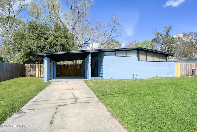 mid-century home with driveway, a front lawn, fence, and an attached carport