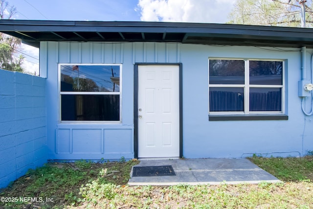 property entrance featuring board and batten siding and concrete block siding