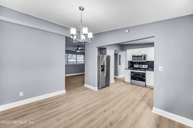 kitchen featuring light wood finished floors, appliances with stainless steel finishes, white cabinetry, and baseboards