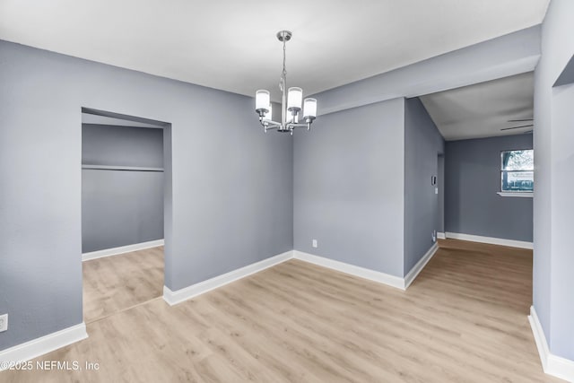 unfurnished dining area with light wood finished floors, an inviting chandelier, and baseboards