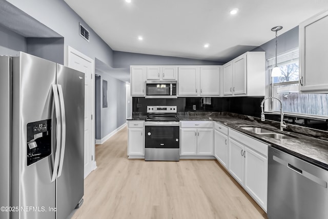 kitchen featuring visible vents, white cabinets, a sink, stainless steel appliances, and backsplash