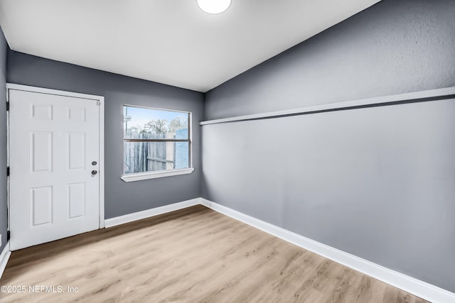 entryway featuring lofted ceiling, baseboards, and wood finished floors