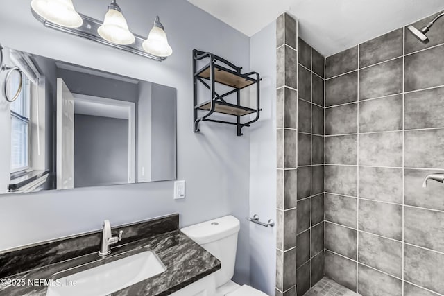 full bathroom with toilet, a tile shower, and vanity