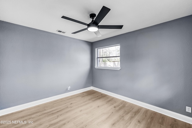 spare room featuring baseboards, visible vents, and wood finished floors